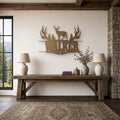 Deer Hunter Name Sign: Antlers, Pines & Rifles in bronze, shown in a mountain lodge living room