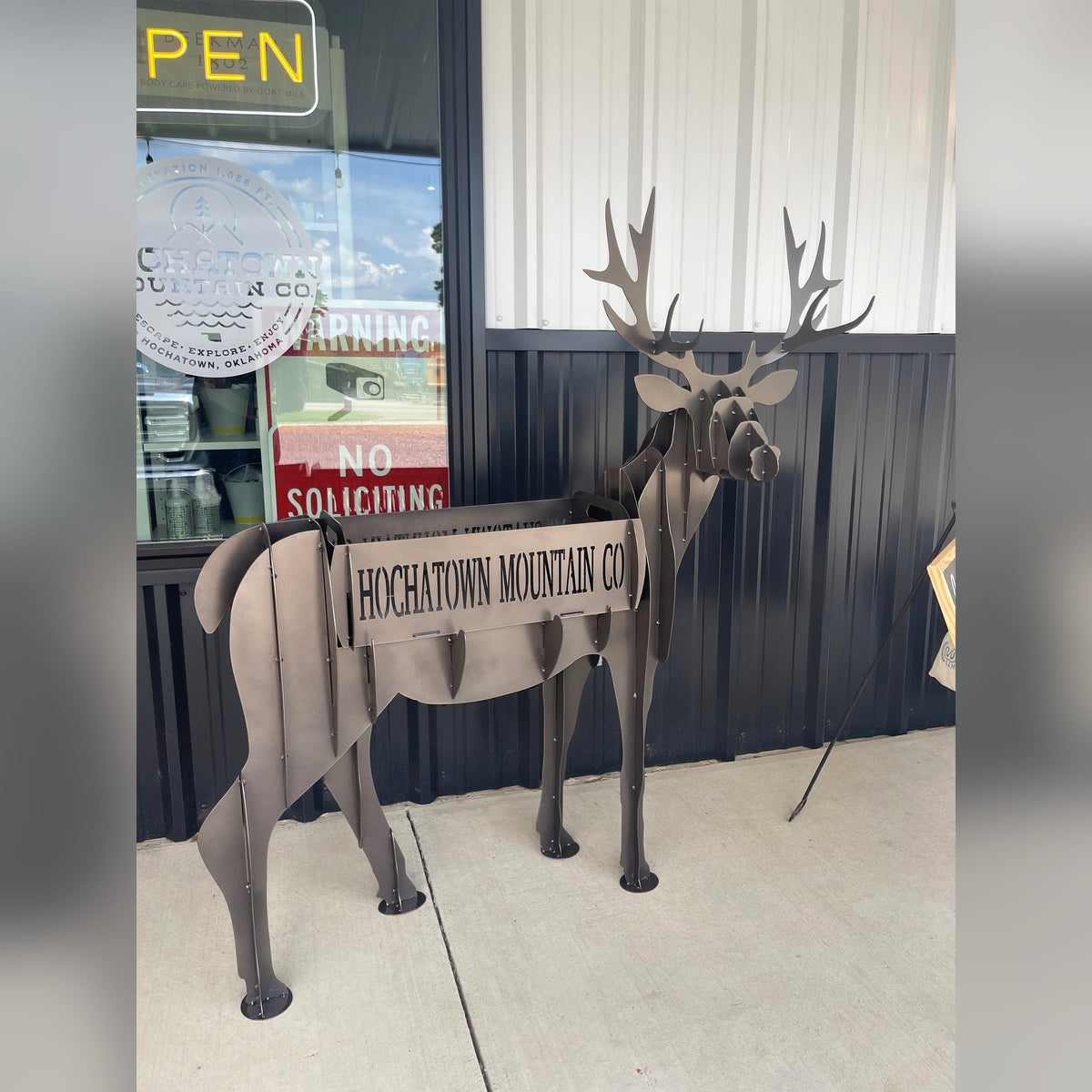 Steel deer planter sculpture with HOCHATOWN MOUNTAIN CO cut into the planter box, outside a storefront in Hochatown, Oklahoma