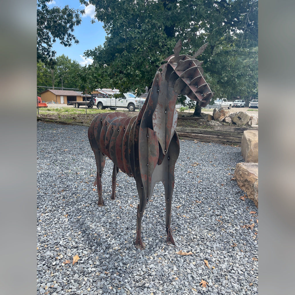 Rusted Corten steel horse sculpture standing on gravel