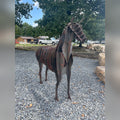 Rusted Corten steel horse sculpture standing on gravel