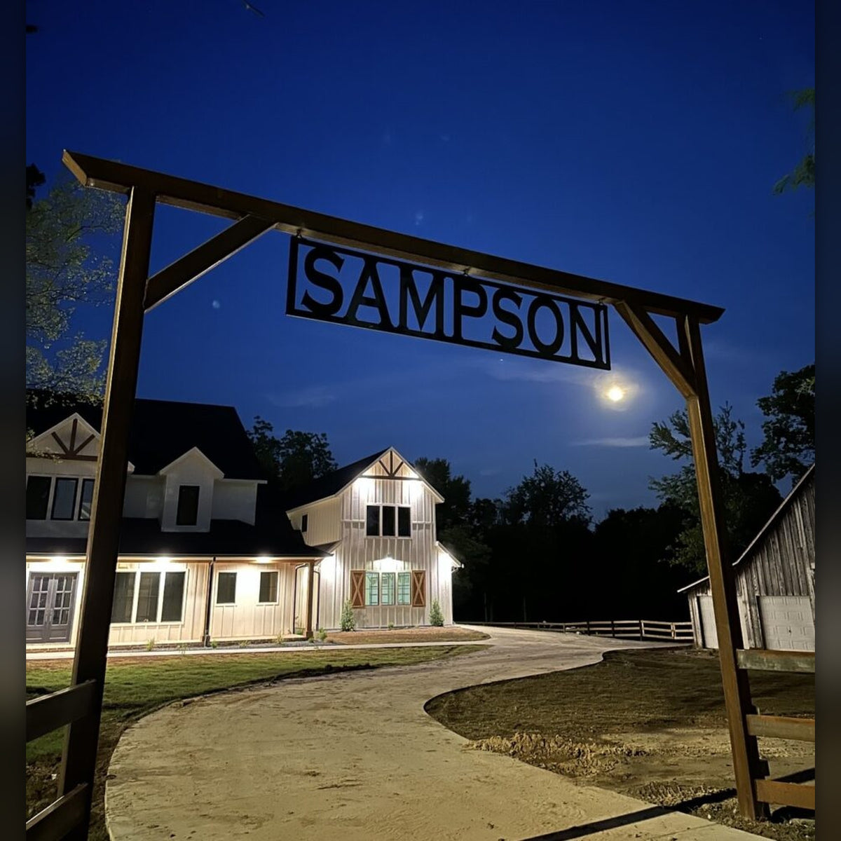 Sampson ranch entrance arch with cut-steel name sign at night