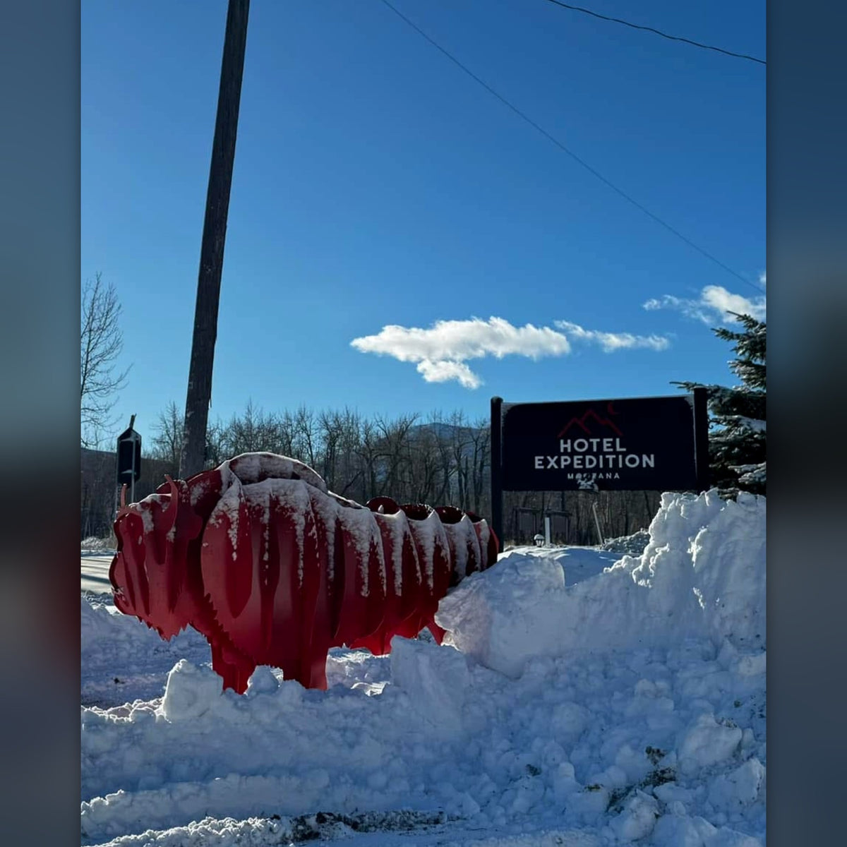 Red steel bison sculpture standing in the snow