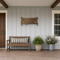 Welcome to Our Lake House Metal Sign with Paddles in bronze, shown in a covered front porch